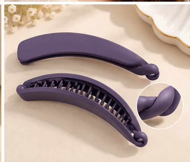 Close-up of an open matte banana hair clip showing the teeth