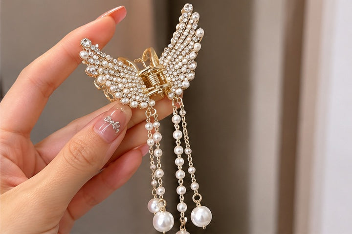 Close-up of butterfly pearl chain hair catcher held in hand
