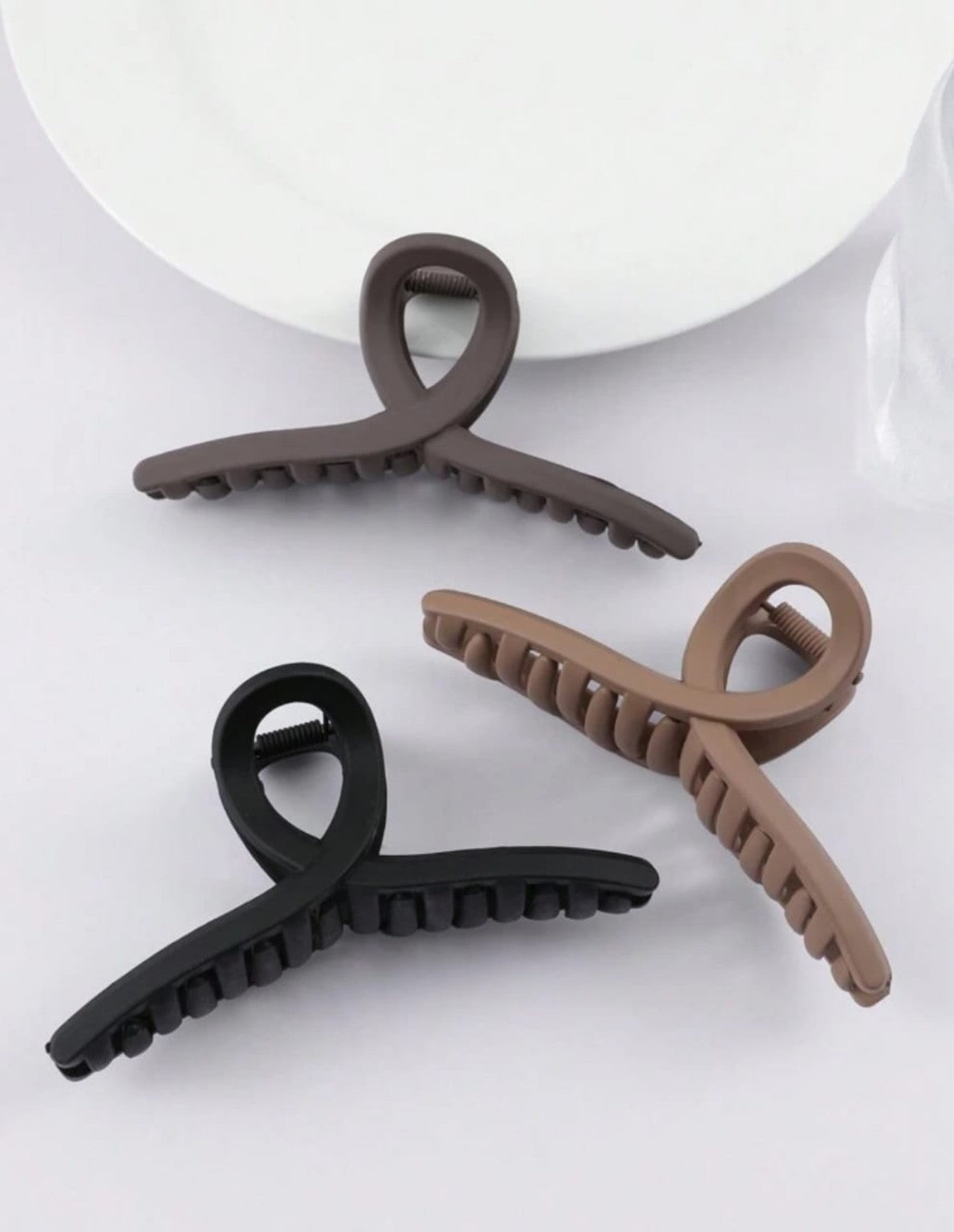Original product photo showing three matte loop-shaped hair claw clips in black, taupe and brown