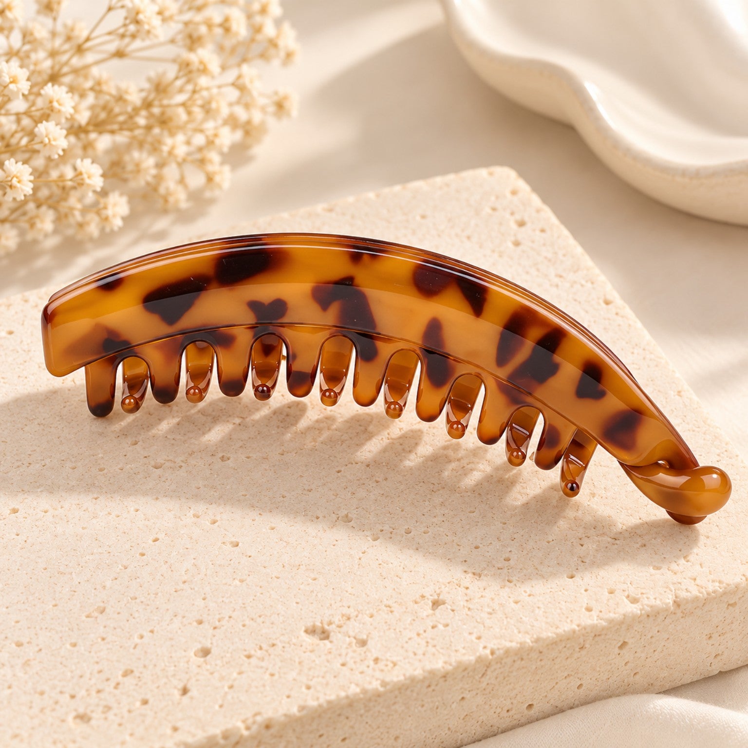 Single amber tortoiseshell banana hair clip on a beige aesthetic product background